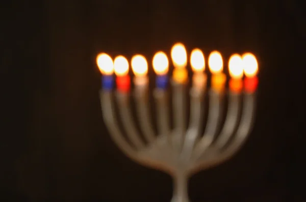 Abstracte onscherpe achtergrond van Joodse vakantie Hanukkah achtergrond met menora (traditionele kandelaar) brandende kaarsen op zwarte achtergrond. — Stockfoto