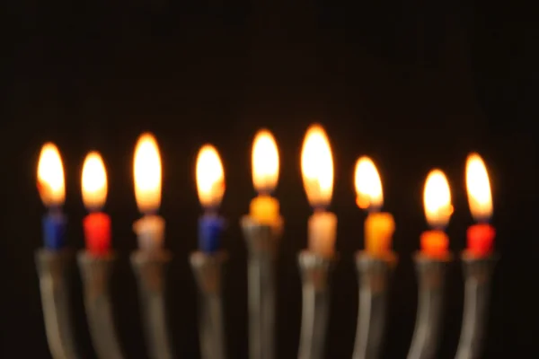 Abstract blurred background of jewish holiday Hanukkah background with menorah (traditional candelabra) Burning candles over black background. — Stock Photo, Image