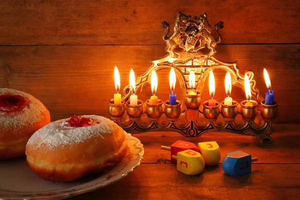 Image of jewish holiday Hanukkah with menorah (traditional Candelabra), donuts. retro filtered image with glitter overlay . — Stock Photo, Image