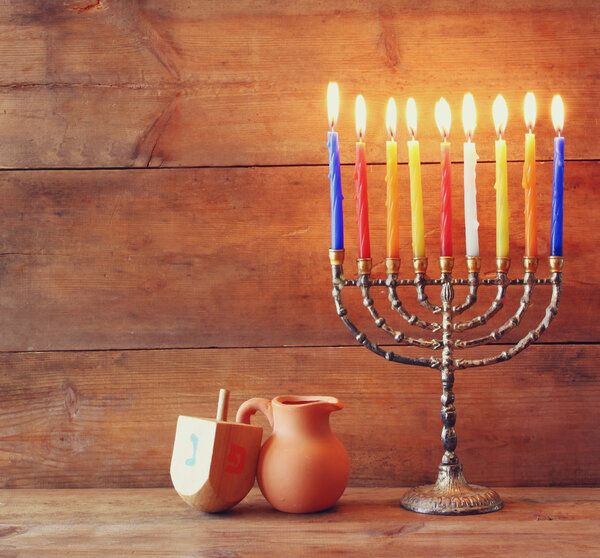 low key image of jewish holiday Hanukkah with menorah (traditional Candelabra) and wooden dreidels (spinning top) .