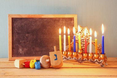 Yahudi tatil Hanukkah menorah (geleneksel Mumluk) ve ahşap kara tahta, metin için yer ile düşük anahtar görüntü.