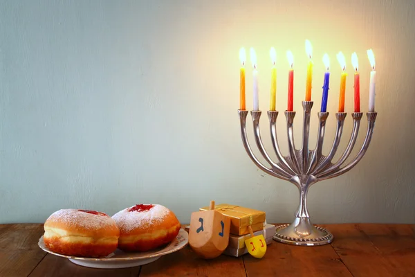 Imagem de férias judaicas Hanukkah com menorah (Candelabra tradicional), rosquinhas e dreidels de madeira (topo de giro). sobreposição de brilho . — Fotografia de Stock