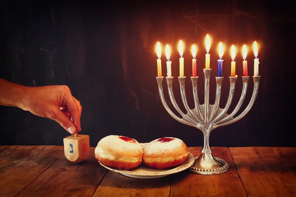 Image of jewish holiday Hanukkah with menorah (traditional Candelabra), donuts and wooden dreidels (spinning top). — Stock Photo, Image