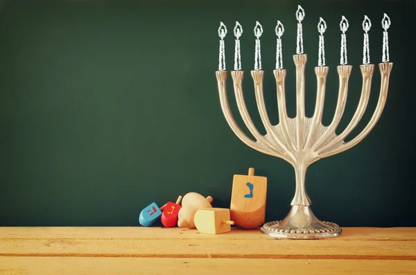 image of jewish holiday Hanukkah with drawing menorah candles (traditional Candelabra), donuts and dreidels (spinning top) over chalkboard background.