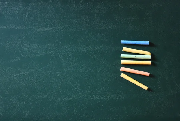 Green chalkboard and collection of chalks — Stock Photo, Image