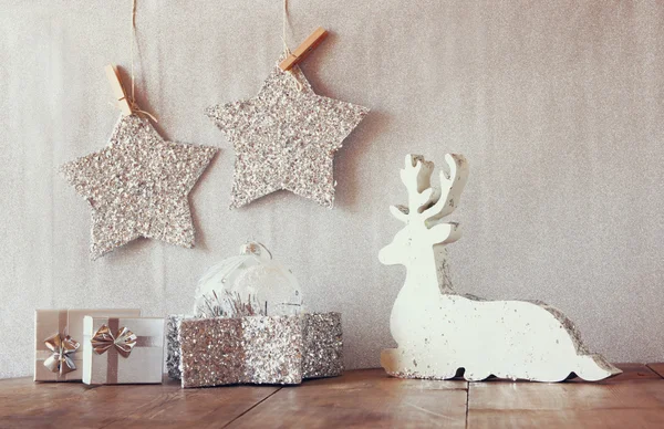 Image of white wooden reindeer and glitter stars hanging on rope over glitter silver background. — 스톡 사진