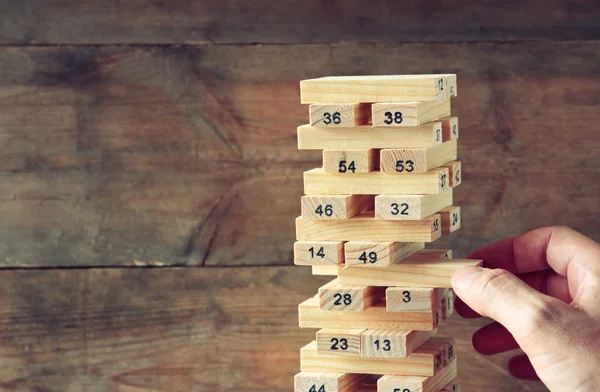 Männerhand legt Holzklötze auf einen Turm. Planung und Strategiekonzept. — Stockfoto