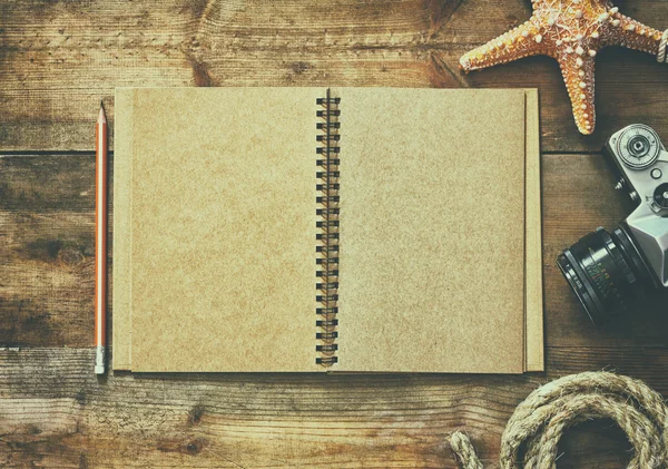 Top view image of open blank notebook, nautical rope, starfish and camera. travel and adventure concept. retro filtered image. — 图库照片