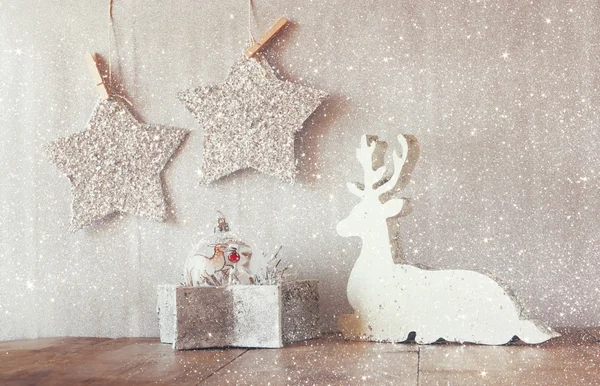Image of white wooden reindeer and glitter stars hanging on rope over glitter silver background. — ストック写真