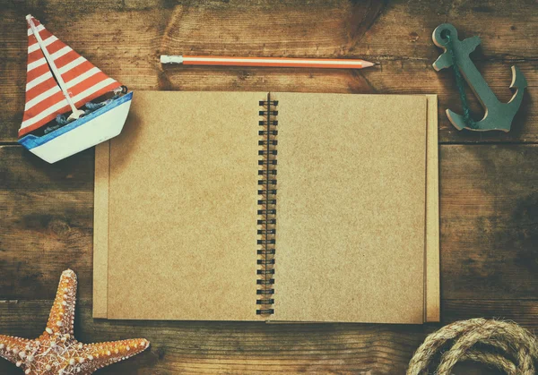 Top view image of open blank notebook, wooden sailboat, nautical rope. travel and adventure concept. retro filtered image. — Φωτογραφία Αρχείου
