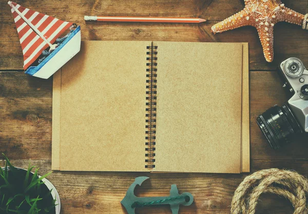 Top view image of open blank notebook, wooden sailboat, nautical rope and camera. travel and adventure concept. retro filtered image. — Stock Photo, Image