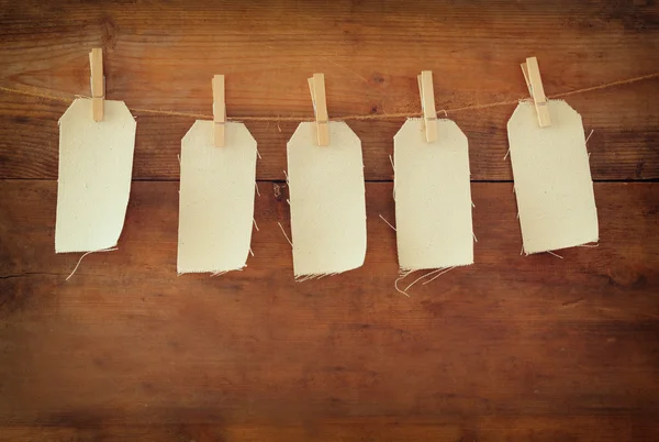 Blank tags hanging on wooden background. — Stock Photo, Image