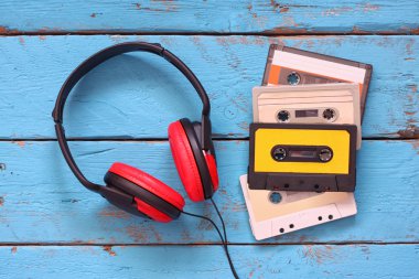 top view of vintage headphones and cassettes over aqua wooden table. retro filtered.
