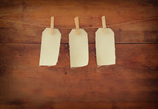 Blank tags hanging on wooden background. — Stock Photo, Image