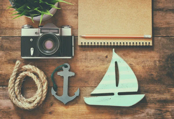 Top view image of notebook, wooden sailboat, nautical rope and camera. travel and adventure concept. retro filtered image. — Stock fotografie