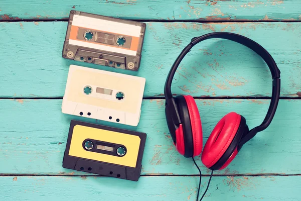 Top view of vintage headphones and cassettes over aqua wooden table. retro filtered. — Stock Fotó