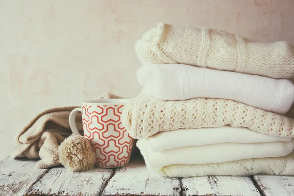 Knitted sweaters next to cup of coffee — Stock Photo, Image