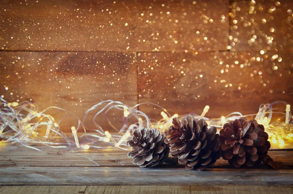 Conos de pino junto a luces de guirnalda de oro —  Fotos de Stock
