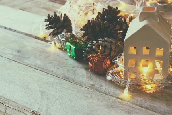 Foto van decoratieve huis en pine kegels op houten achtergrond. Kopieer ruimte. Retro gefilterd. — Stockfoto