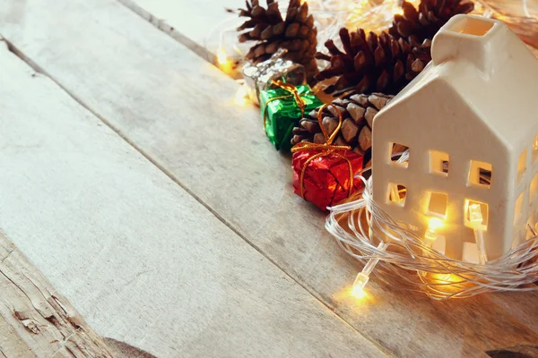 Foto van decoratieve huis en pine kegels op houten achtergrond. Kopieer ruimte. Retro gefilterd. — Stockfoto