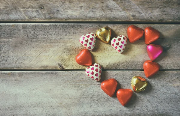 Bovenaanzicht afbeelding van kleurrijke hart vorm chocolade op houten tafel. Valentine's day viering concept. — Stockfoto
