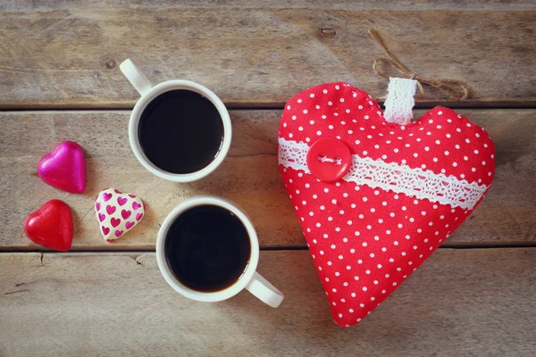 Top view image of colorful heart shape chocolates, fabric heart and couple mugs of coffee  on wooden table. valentine's day celebration concept. — Stok fotoğraf