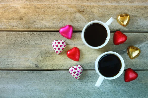 Imagem vista superior de chocolates forma de coração colorido e canecas par de café na mesa de madeira. Conceito de celebração do dia dos namorados . — Fotografia de Stock