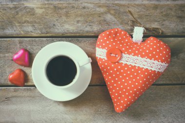 top view image of colorful heart shape chocolates, fabric heart and cup of coffee on wooden table. valentine's day celebration concept.