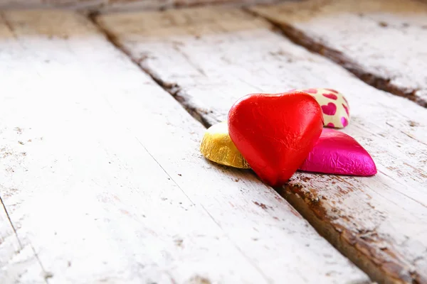 Bovenaanzicht afbeelding van kleurrijke hart vorm chocolade op houten tafel. Valentine's day viering concept. — Stockfoto