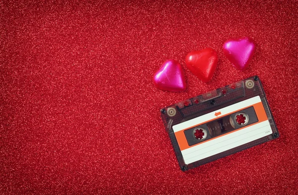 Top view image of colorful heart shape chocolates and audio cassette on red glitter background. valentine's day celebration concept. — ストック写真