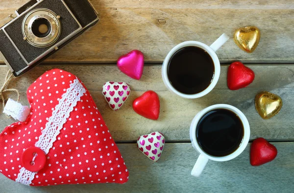 Top view image of colorful heart shape chocolates, fabric heart and couple mugs of coffee on wooden table. valentine's day celebration concept. — Stock Fotó