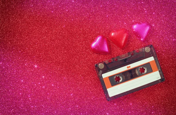 Imagem vista superior de chocolates forma de coração colorido e cassete de áudio no fundo brilho vermelho. Conceito de celebração do dia dos namorados . — Fotografia de Stock