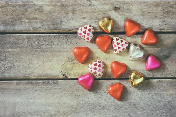 Top view image of colorful heart shape chocolates on wooden table. valentine's day celebration concept. retro filtered ans toned image. — Stockfoto