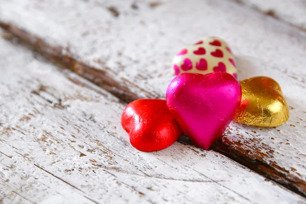 Top view image of colorful heart shape chocolates on wooden table. valentine's day celebration concept. retro filtered ans toned image. — Stockfoto