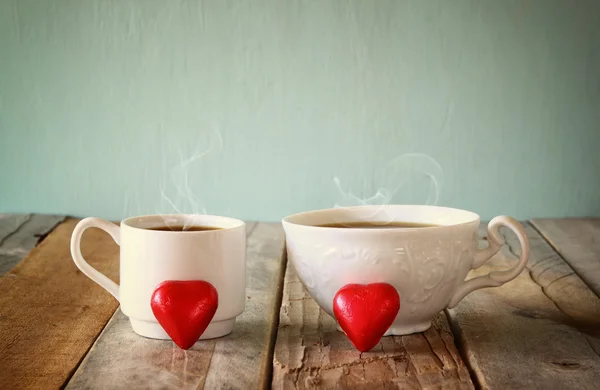 Imagem de dois chocolates em forma de coração vermelho e duas xícaras de café na mesa de madeira. Conceito de celebração do dia dos namorados. vintage filtrado . — Fotografia de Stock