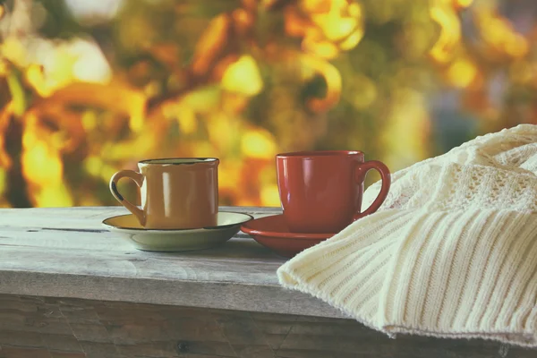 Vorderbild von zwei Kaffeetassen über Holztisch und Wollpullover vor herbstlichem Sonnenuntergang. Valentinstag-Konzept. — Stockfoto