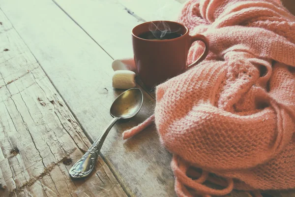 Foto enfoque selectivo de la bufanda de punto acogedor rosa con a taza de café en una mesa de madera. espacio de trabajo o descanso para café . — Foto de Stock