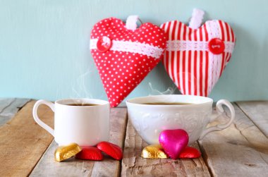 iki kırmızı kalp şekli çikolata ve iki bardak kahve ahşap masa üzerinde görüntü. Sevgililer günü kutlama kavramı. Filtre vintage.