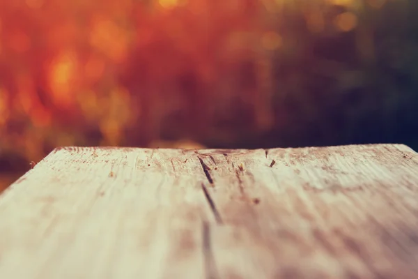 Rustic wood table in front of autumnal blurred background. filtered image.  product display and picnic concept. selective focus. — Stock Photo, Image