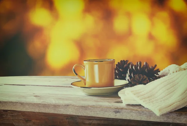 Image avant de la tasse à café sur une table en bois et un pull en laine devant le fond du coucher de soleil automnal. filtré rétro . — Photo