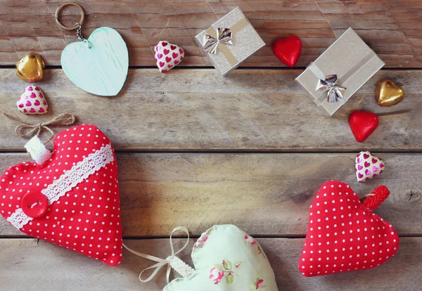Top view image of colorful heart shape chocolates, fabric hearts and gift boxes on wooden table. valentine's day celebration concept. — Stockfoto