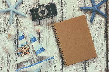 top view image of blank notebook, wooden sailboat, starfish, shells and camera. travel and adventure concept
