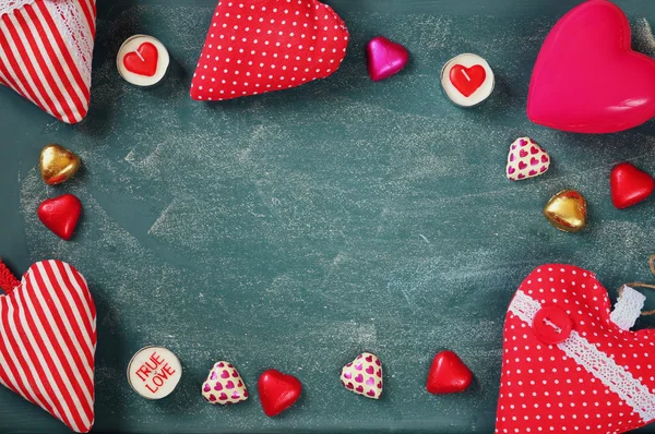 Top view image of  colorful heart shape chocolates, fabric hearts on blackboard background. valentine's day celebration concept — Stockfoto