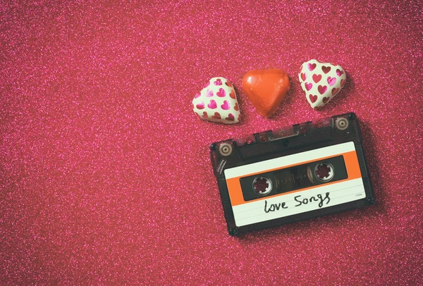Верхний вид изображения красочной формы сердца шоколад и аудиокассеты на красном блеске фона. День святого Валентина — стоковое фото