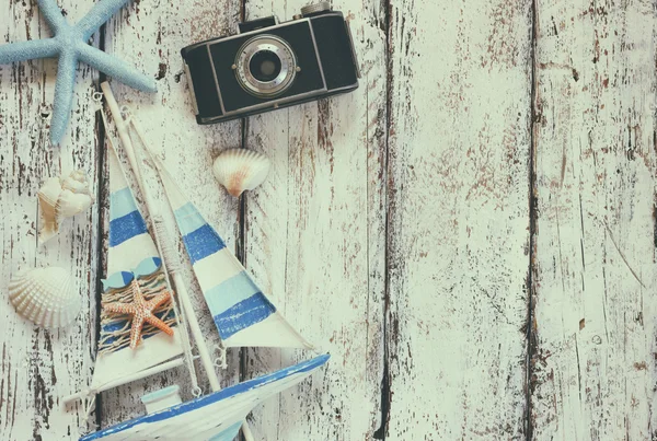 Top view image of photo camera, wood boat, sea shells and star fish over wooden table — Stock Photo, Image