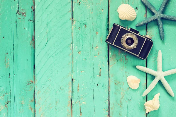 Κάτοψη εικόνας φωτογραφική μηχανή φωτογραφιών, θαλάσσια όστρακα και ψάρια αστέρι πέρα από το ξύλινο τραπέζι — Φωτογραφία Αρχείου