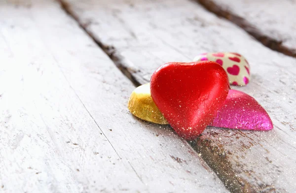 Imagen de vista superior de chocolates en forma de corazón de colores en la mesa de madera. Concepto de celebración del día de San Valentín. enfoque selectivo —  Fotos de Stock