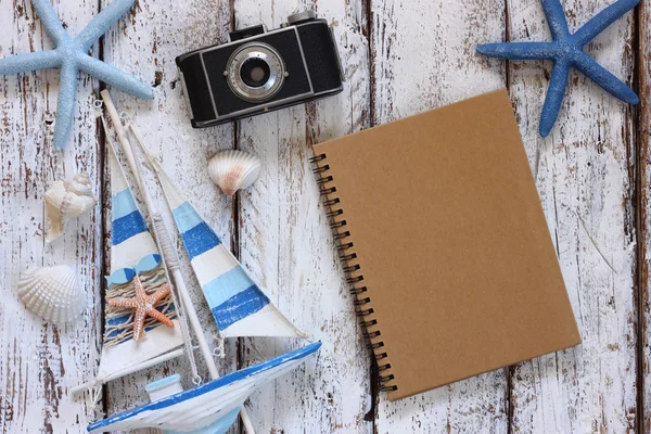 Top view image of blank notebook, wooden sailboat, starfish, shells and camera. travel and adventure concept — Stock Photo, Image