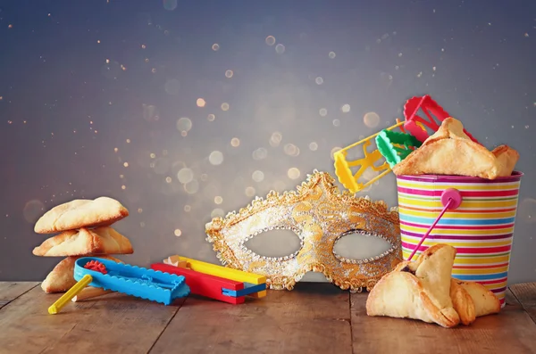 Hamantaschen cookies or hamans ears,noisemaker and mask for Purim celebration (jewish carnival holiday) and glitter background. selective focus — Stock Photo, Image