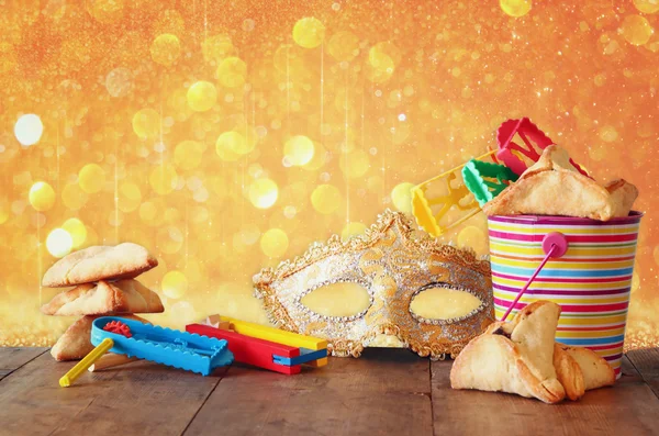 Hamantaschen cookies or hamans ears,noisemaker and mask for Purim celebration (jewish carnival holiday) and glitter background. selective focus — Stock Photo, Image